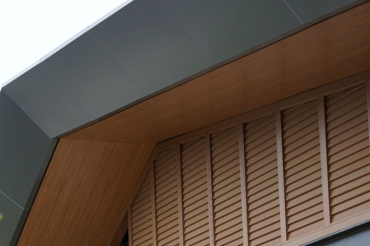 Wood-look louver windows installed beneath a modern home roofline