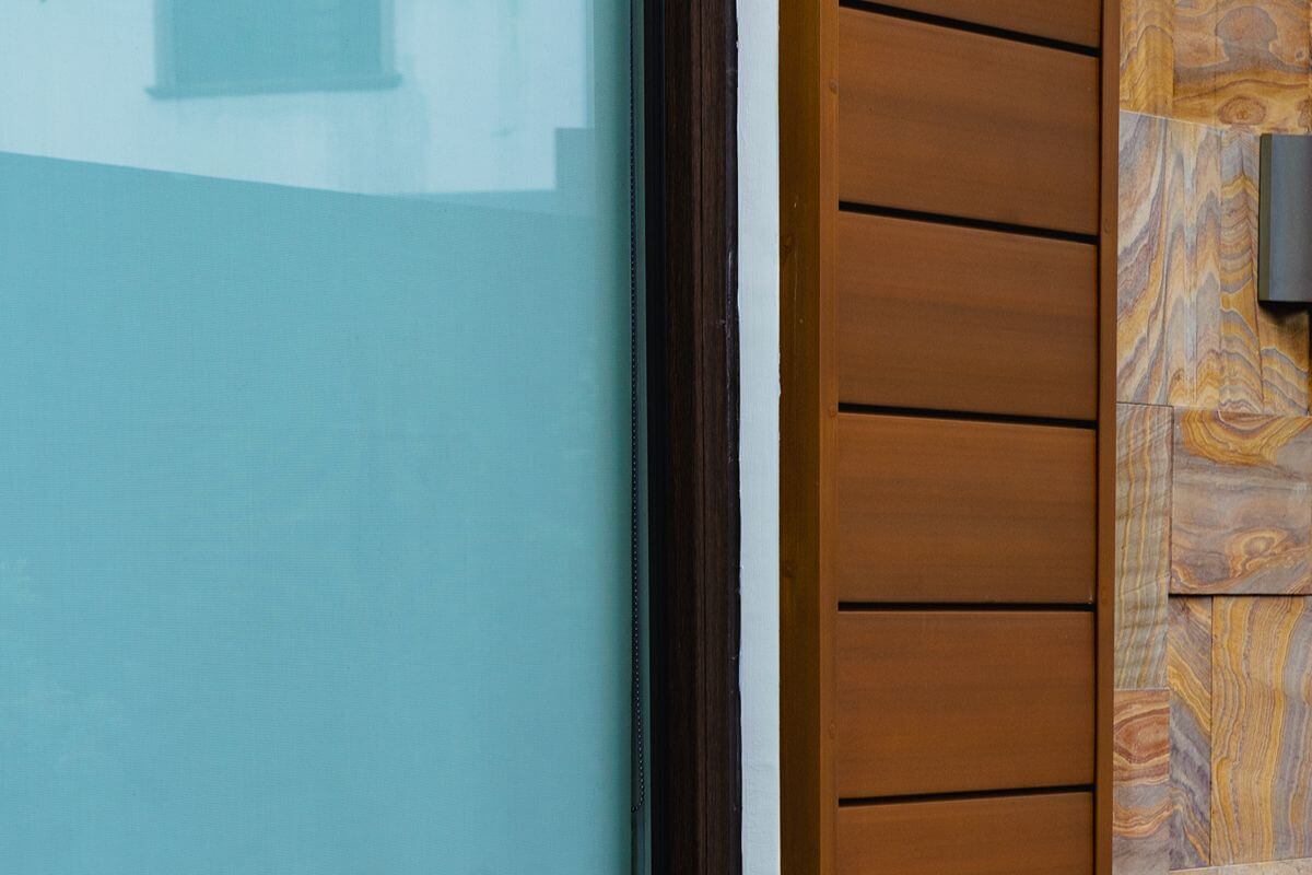 WPC wall cladding beside glass and stone finishes, showing a polished wood-look surface for branded spaces