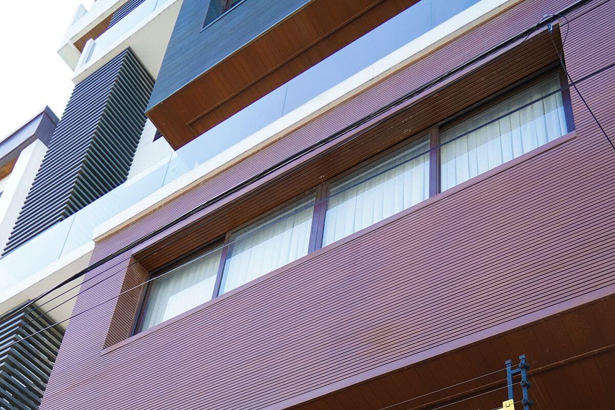 Multi-story building facade with WPC-style cladding, windows, and architectural exterior panels