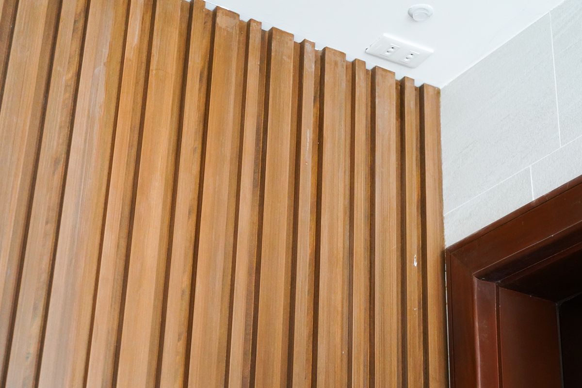 Close-up of vertical wood-look cladding beside a doorway, showing textured slats and clean corner detailing