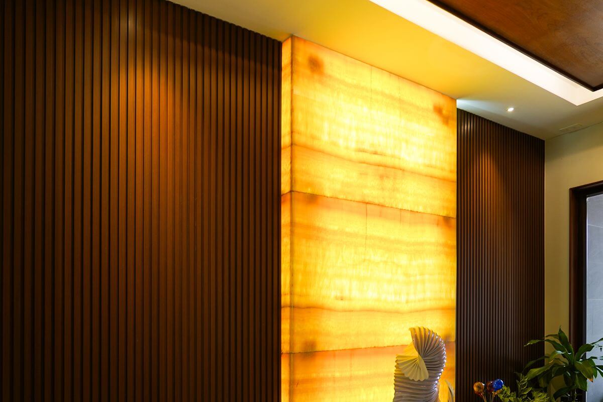 Warm interior with WPC wall cladding panels, illuminated accent wall, and plants supporting biophilic design