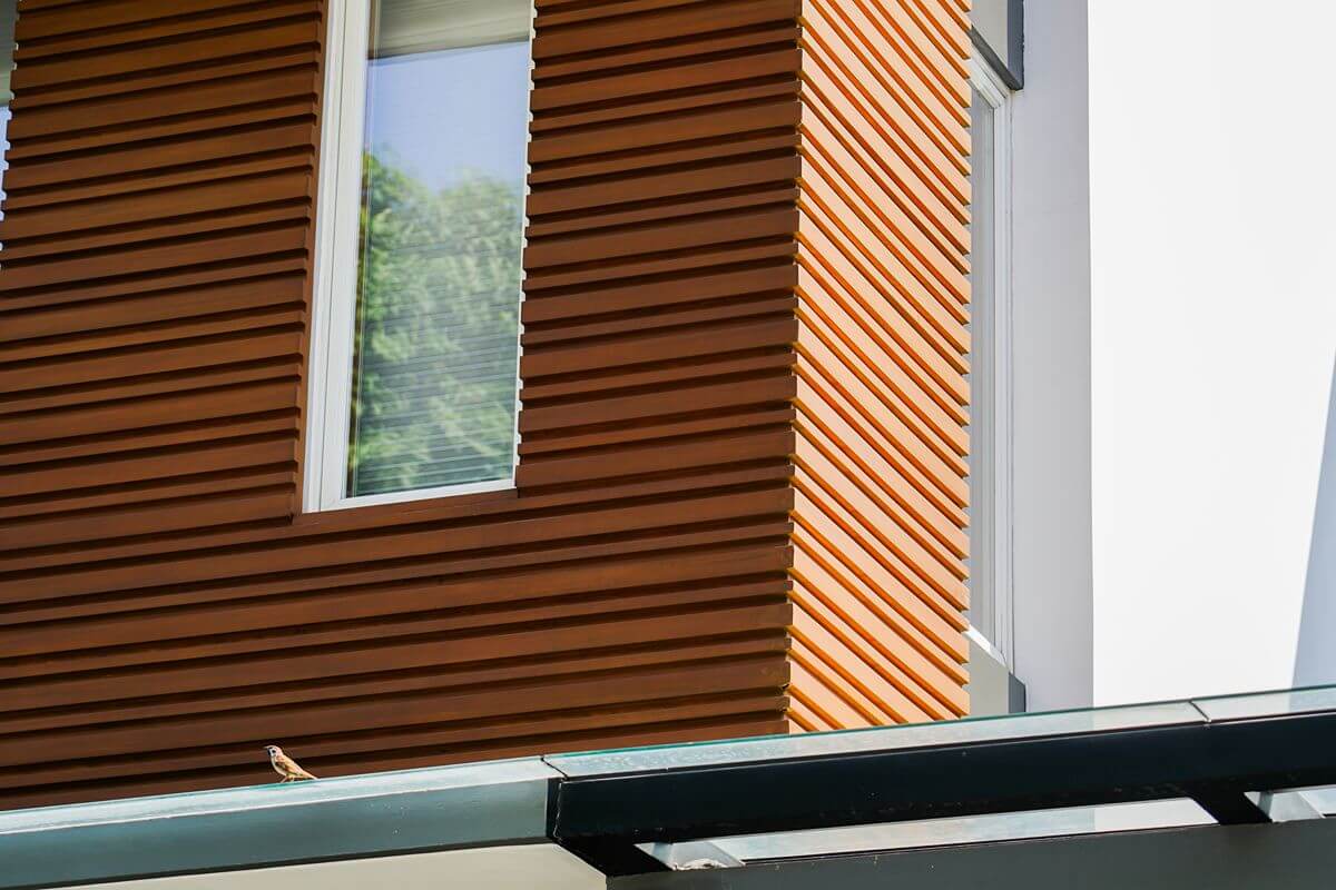 Exterior wall with horizontal wood slats and a window, showing wood-inspired architectural texture and depth